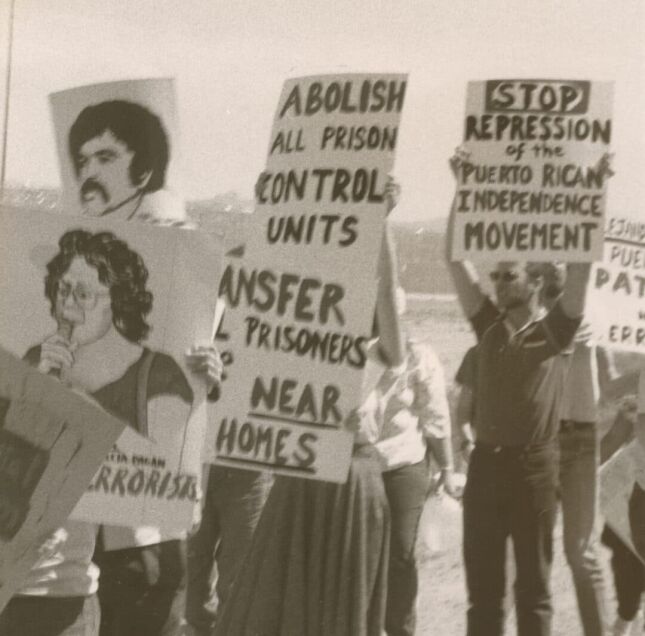 Black and white photo of Puerto Rican activists with signs about the Puerto Rican Independence Movement and the abolishment of prison control units