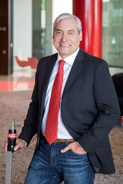 Alfredo Rivera standing holding a bottle of Coca-Cola