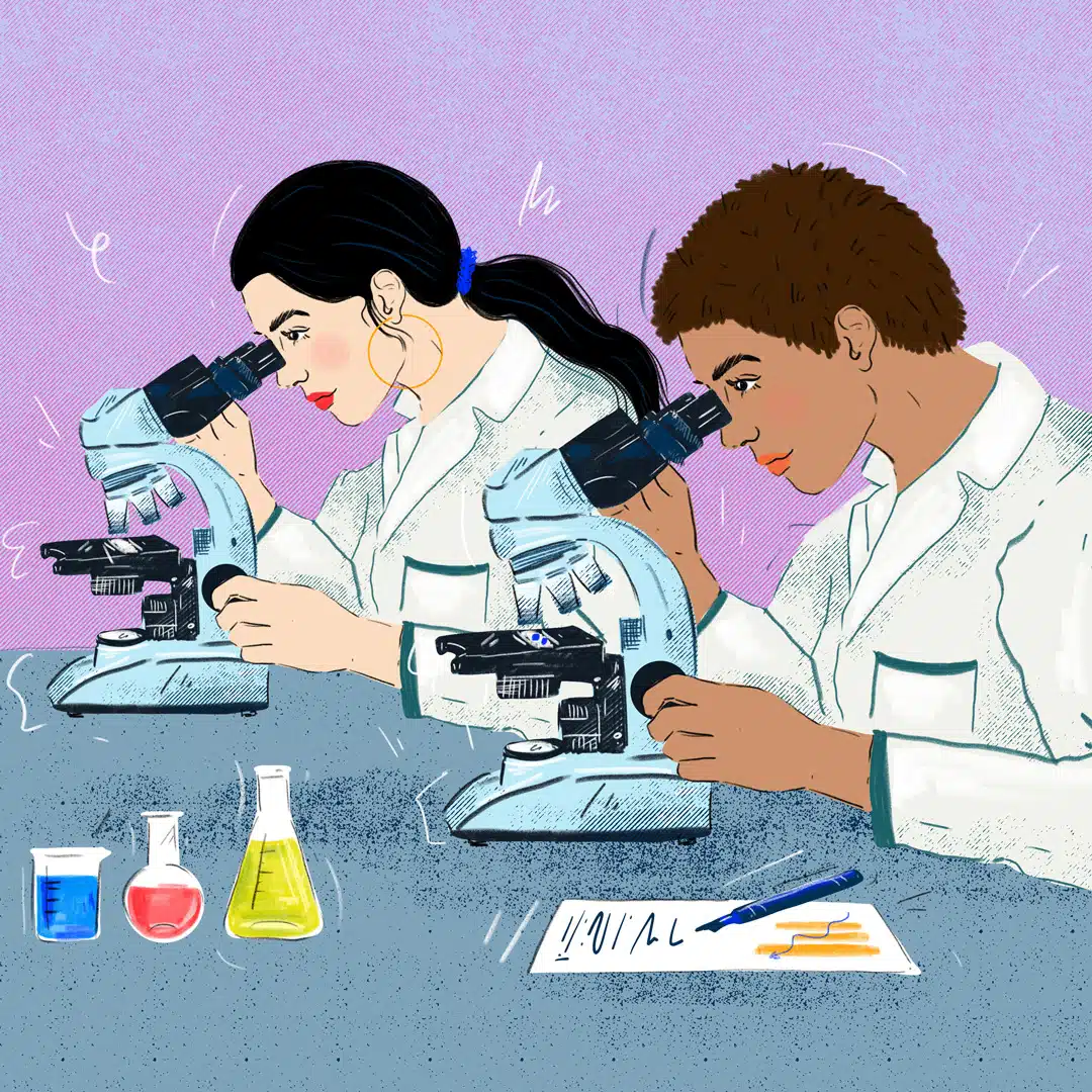 Two women scientists of color look into their respective microscopes to study material. They are both wearing lab coats and surrounded by various solutions and a document with their notes on it.