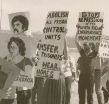 Black and white photo of Puerto Rican activists with signs about the Puerto Rican Independence Movement and the abolishment of prison control units