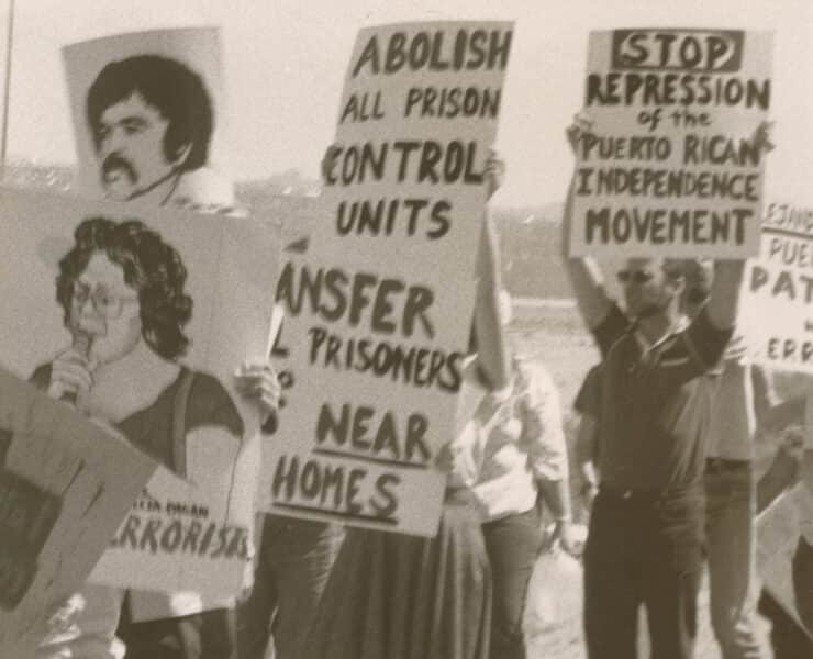 Black and white photo of Puerto Rican activists with signs about the Puerto Rican Independence Movement and the abolishment of prison control units