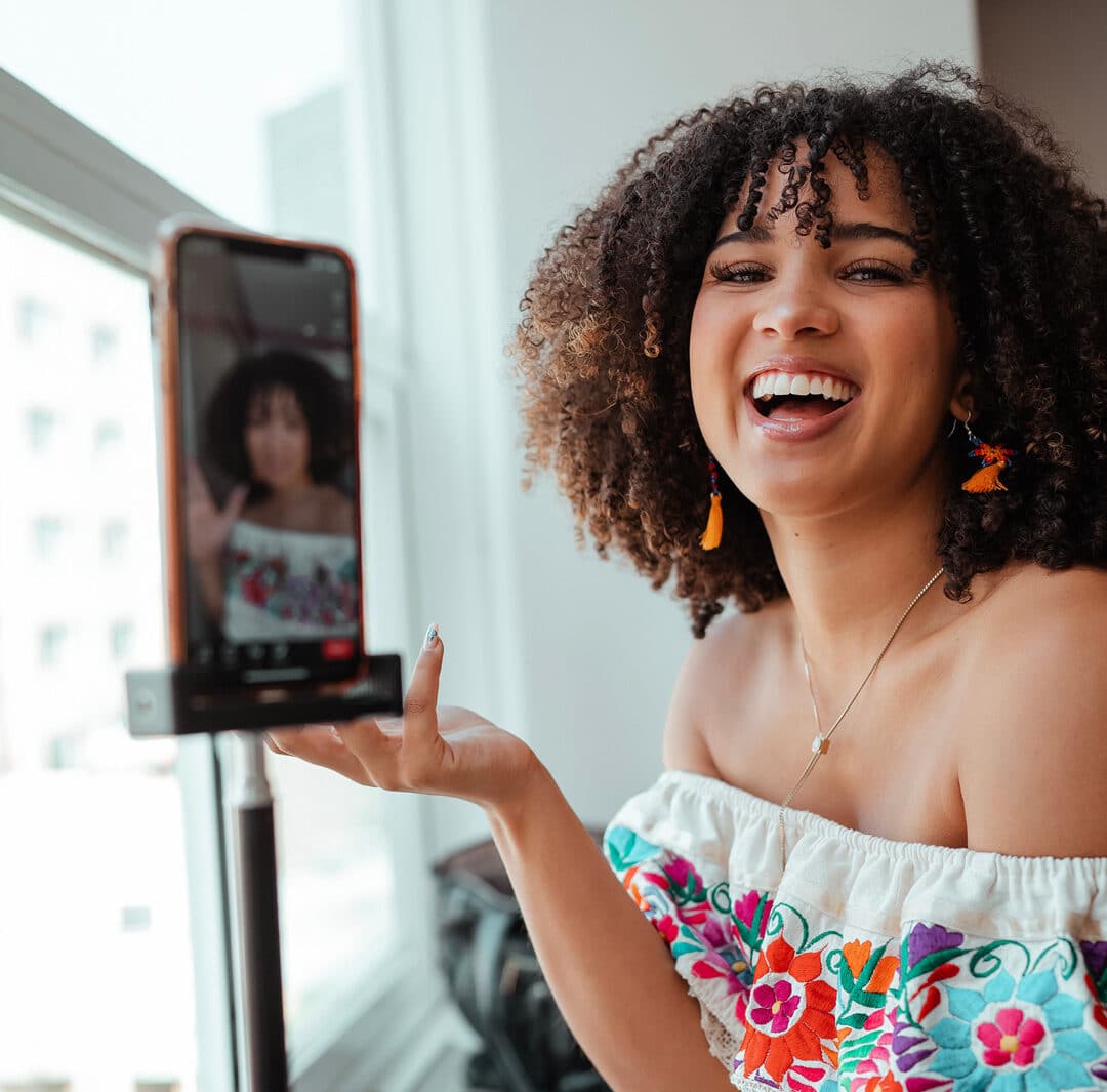 An Afro-Latina woman holds up her iphone to the camera while laughing