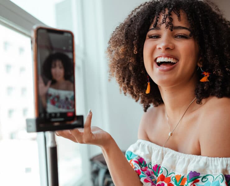 An Afro-Latina woman holds up her iphone to the camera while laughing