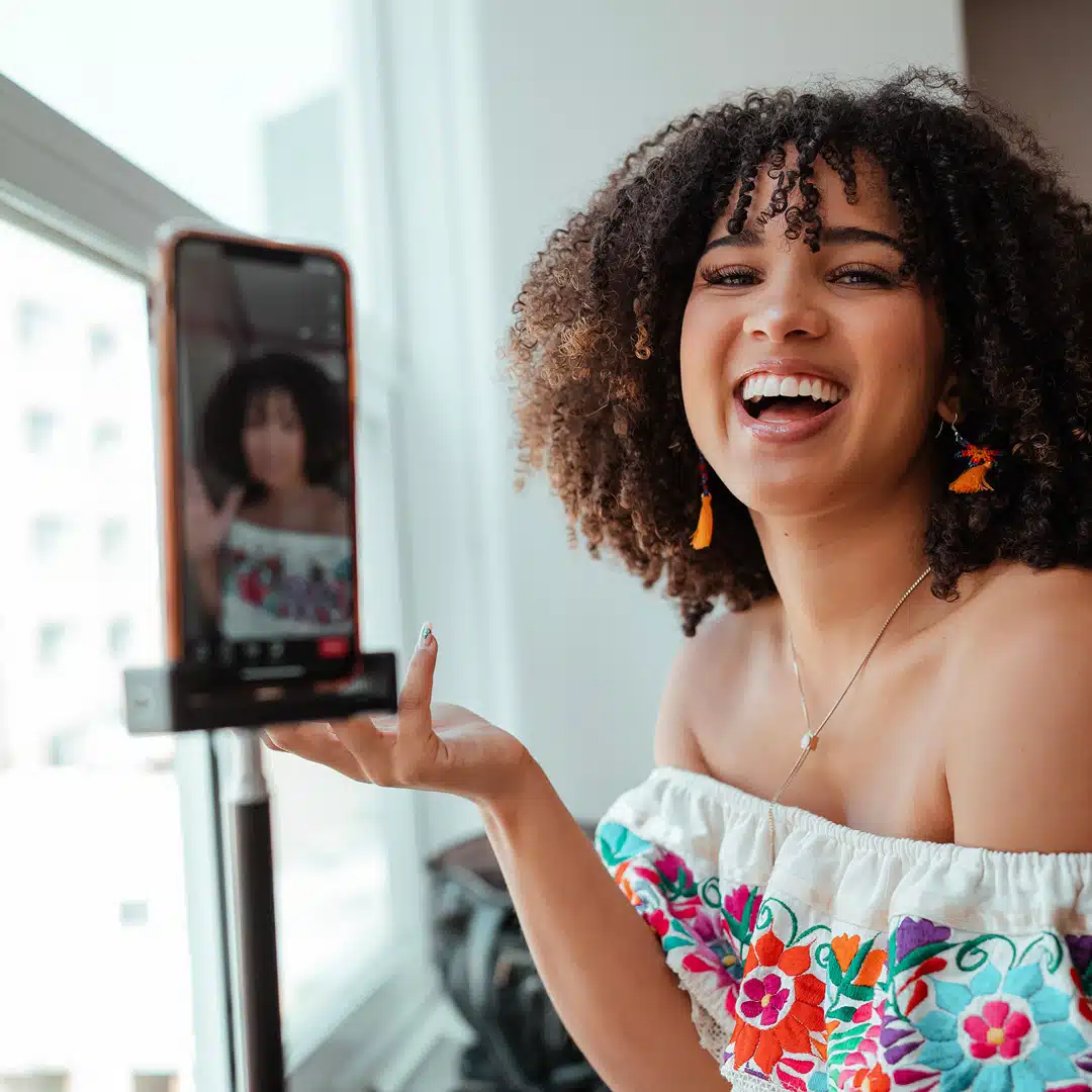 An Afro-Latina woman holds up her iphone to the camera while laughing