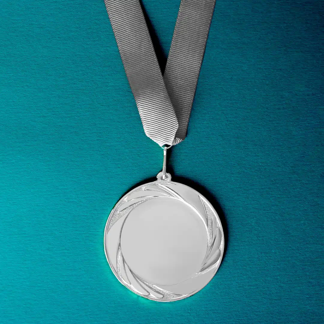 A silver medal lays flat on a teal background