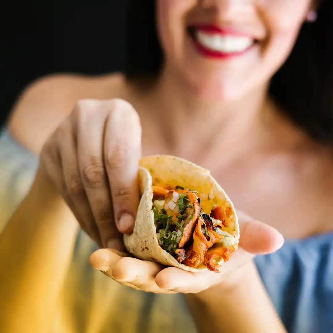 A woman cups an al pastor taco in her hands