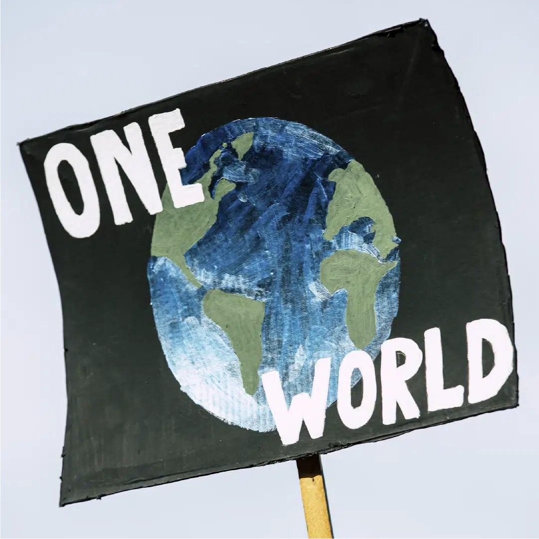 A picketing poster picturing the globe against a black background with the words "ONE WORLD" in white