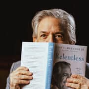 Luis A. Miranda Jr. holds his memoir Relentless open with the cover facing out, and the book is cover all but his eyes and the top of his head